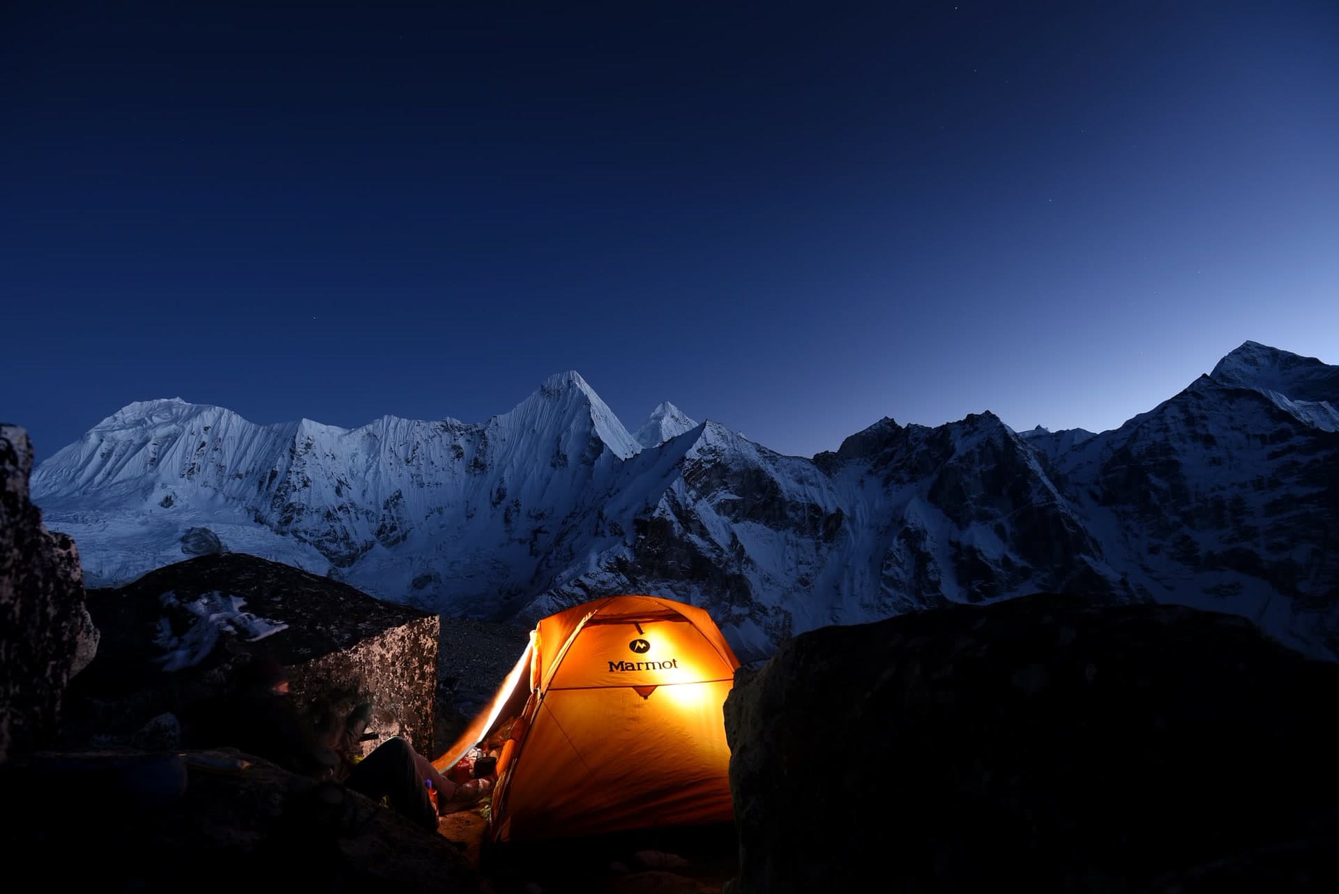 The Himalaya at blue hour above a lit camp